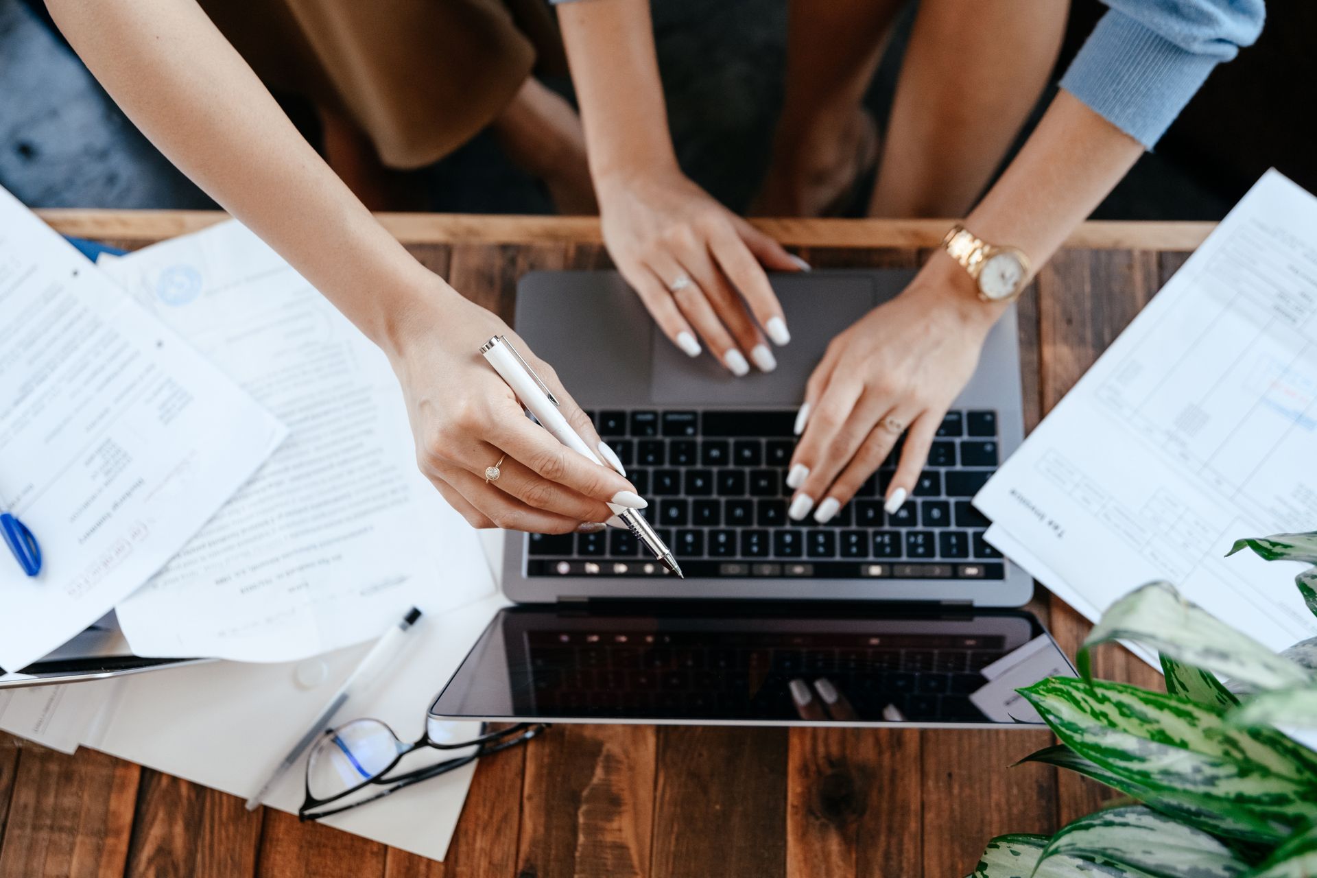 Mains sur un ordinateur portable entourées de documents de travail